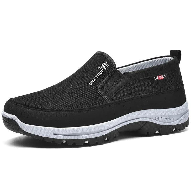 Musta slip on -kenkä holvikaarituellisella pohjalla valkoisella taustalla