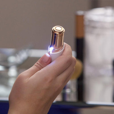 Käsi pitelee kasvotrimmeriä LED-valo päällä