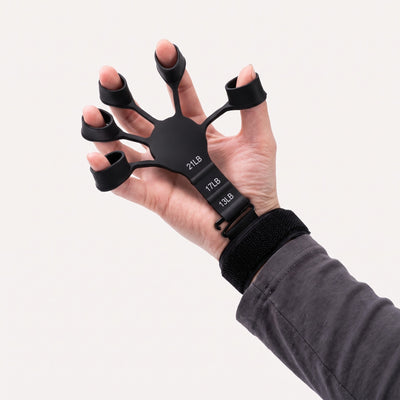 Kädessä sormivoimaharjoitin viidellä sormilenkillä