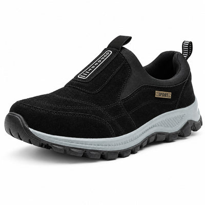 Svarta slip-on-skor med grå greppande sula, snett framifrån