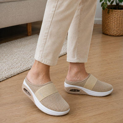 Beige tofflor som bärs på trägolv hemma